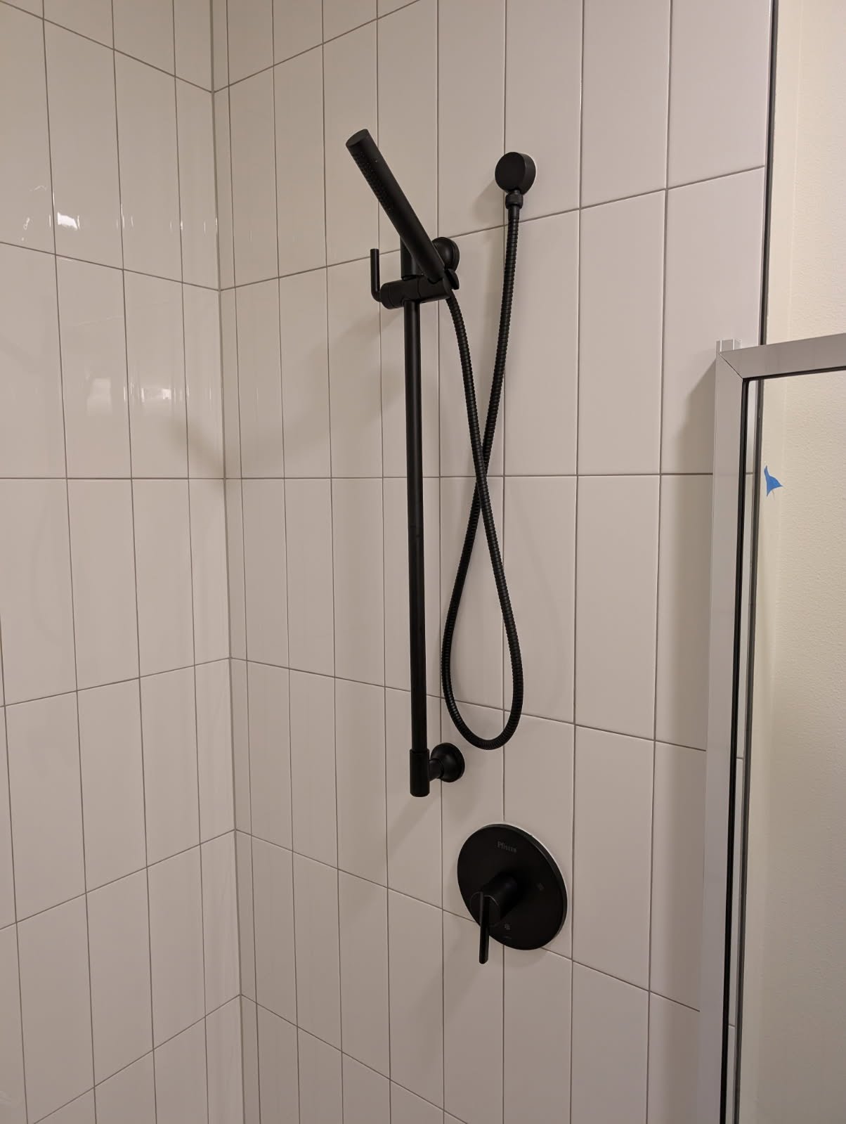 Matte black shower valve and hand-held slide bar on subway tile